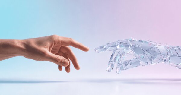 Mano humana y mano de cristal translúcido casi tocándose